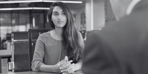 Woman sits with her hands folded during an interview